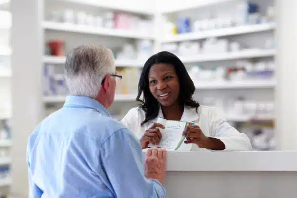 Older man speaking with a pharmacist at a pharmacy counter