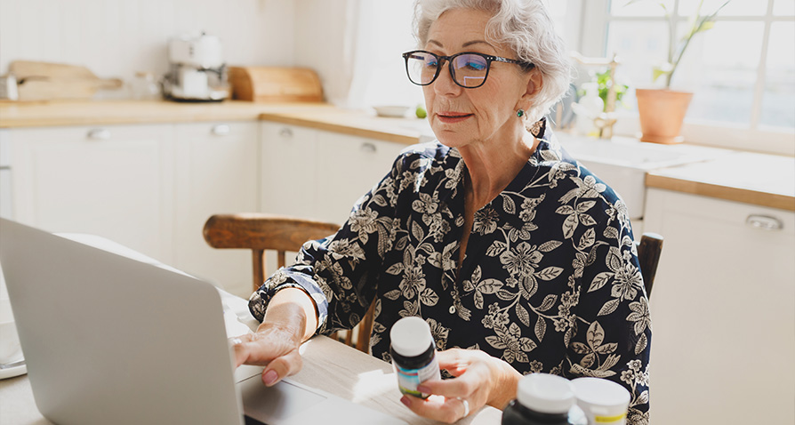 An older woman checks her current prescriptions with a new insurance plan's formulary.